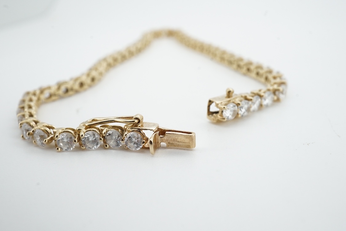 A modern yellow metal (stamped 585) and cubic zirconia set line bracelet, 18cm and a pair of similar drop earrings, together with a similar 9k and cubic zirconia set cluster ring, size N.